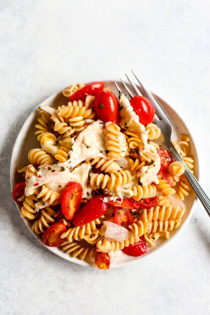 Simple caprese pasta bake on white plate with fork