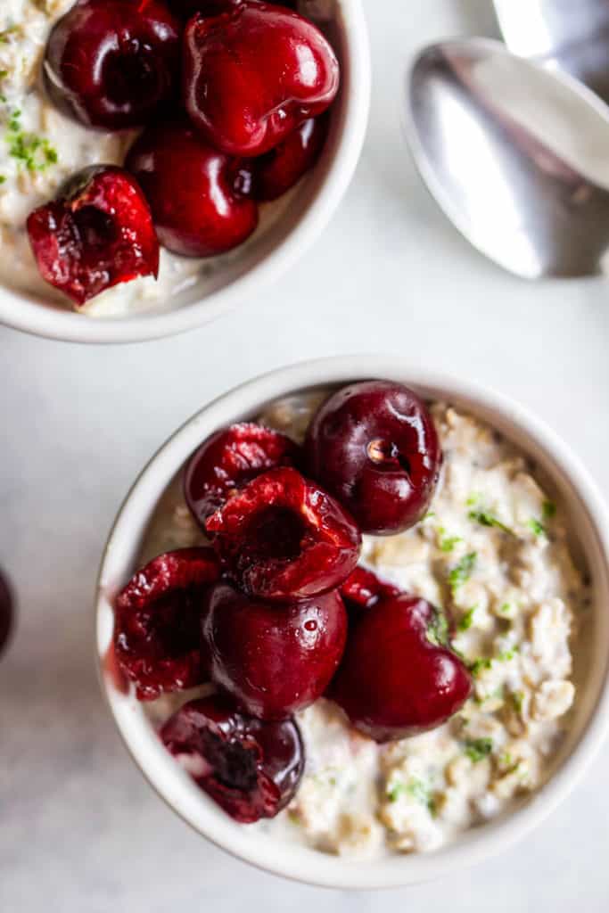 Cherry lime overnight oats in small white bowl with spoon