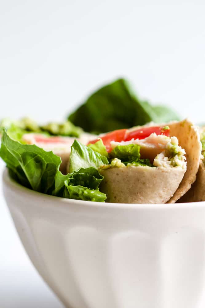 Whole wheat turkey wraps in white bowl with romaine lettuce leaves