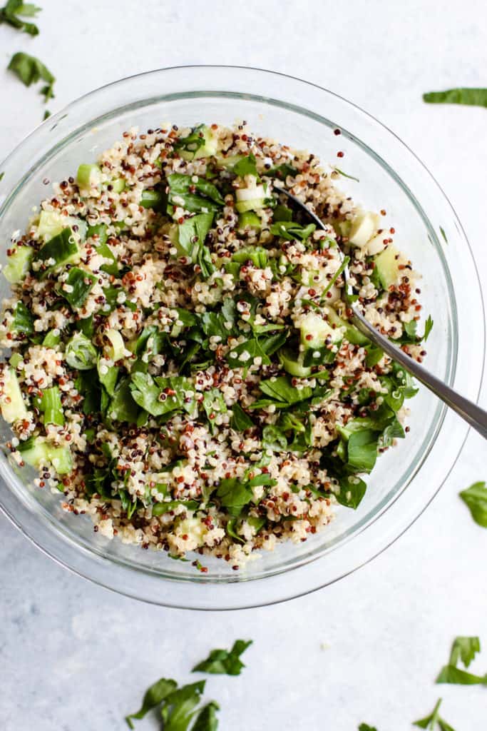 Simple detox quinoa salad in clear glass bowl with spoon
