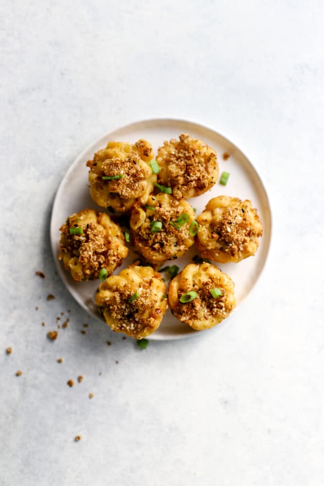 Healthy mac and cheese bites topped with green onions on white plate
