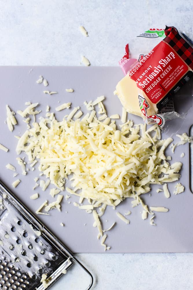 Grated cheddar cheese on gray cutting board