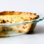 Simple quiche with chickpea flour baked in clear glass pie dish with slice taken out
