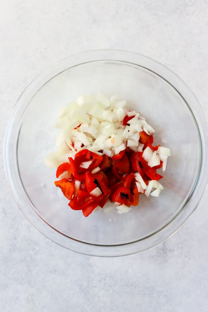 Roasted red peppers and onions in a clear glass bowl