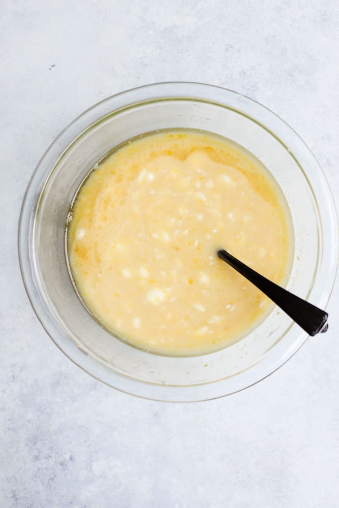 Melted coconut oil, honey, eggs, Greek yogurt, vanilla, and lemon juice whisked together in a clear bowl with fork