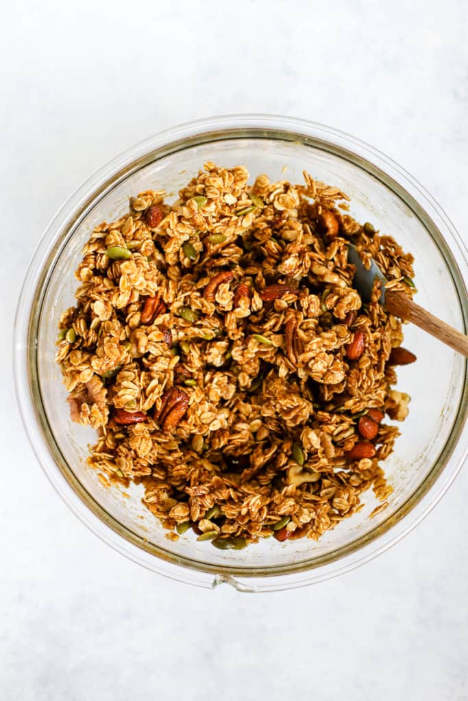 Pumpkin granola ingredients mixed in clear glass bowl