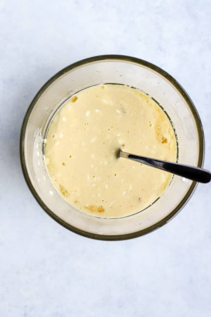 Coconut oil, maple syrup, eggs, Greek yogurt, vanilla, and orange juice whisked together in clear glass bowl