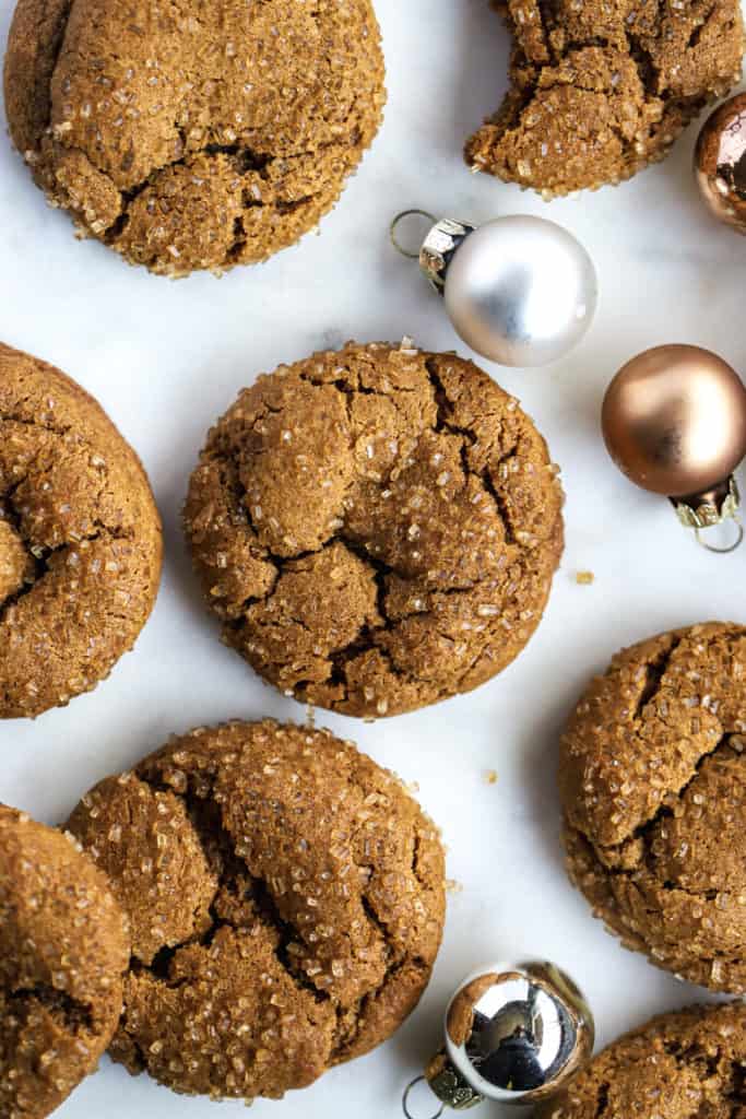 Healthier soft ginger molasses cookies on white marble surface, with a few small holiday ornaments
