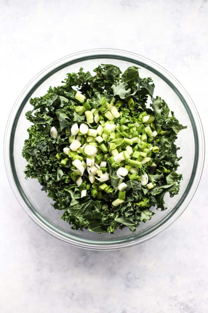 Shredded curly kale and sliced green onions in clear glass bowl