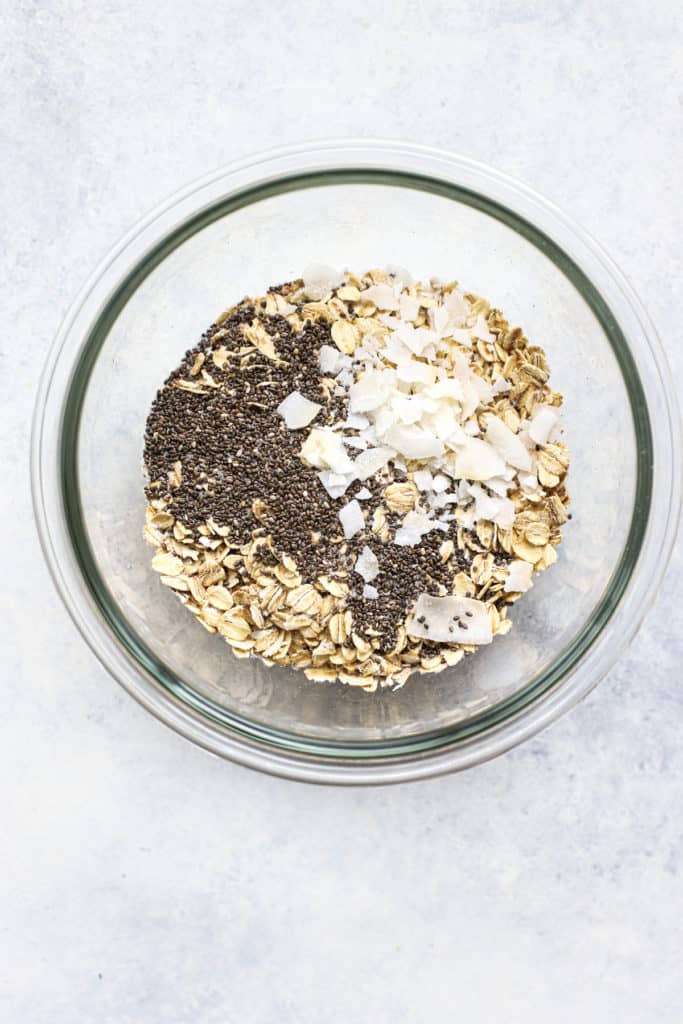 Oats, chia seeds, and coconut flakes in clear glass bowl