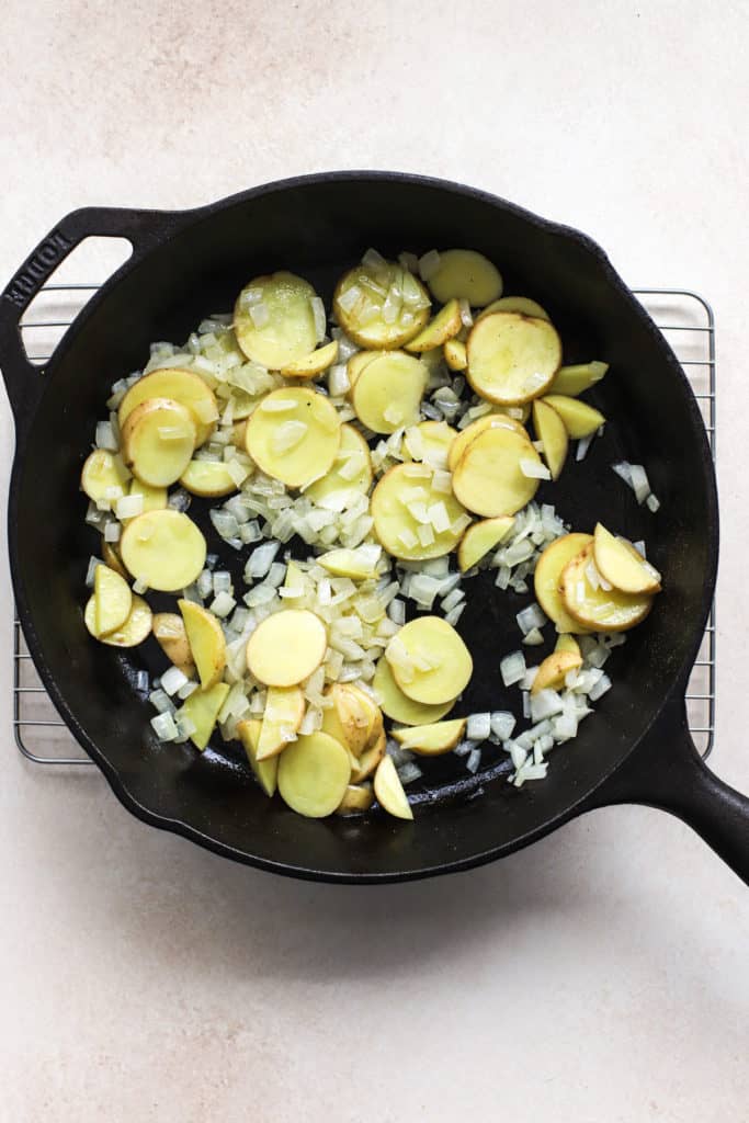 Thinly sliced Yukon gold potatoes and diced onions sautéed in black cast iron skillet