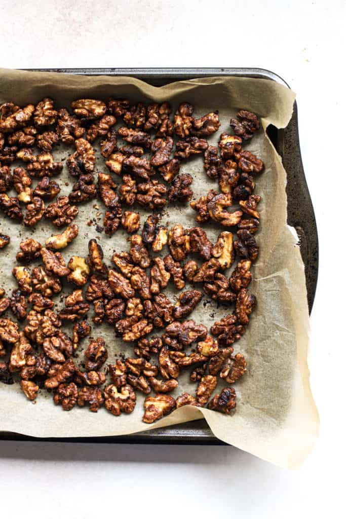Cayenne maple toasted walnuts on parchment lined baking sheet