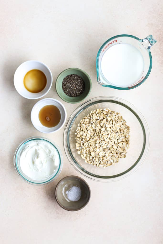 Protein overnight oats ingredients, including milk, vanilla extract, chia seeds, maple syrup, oats, yogurt, and salt