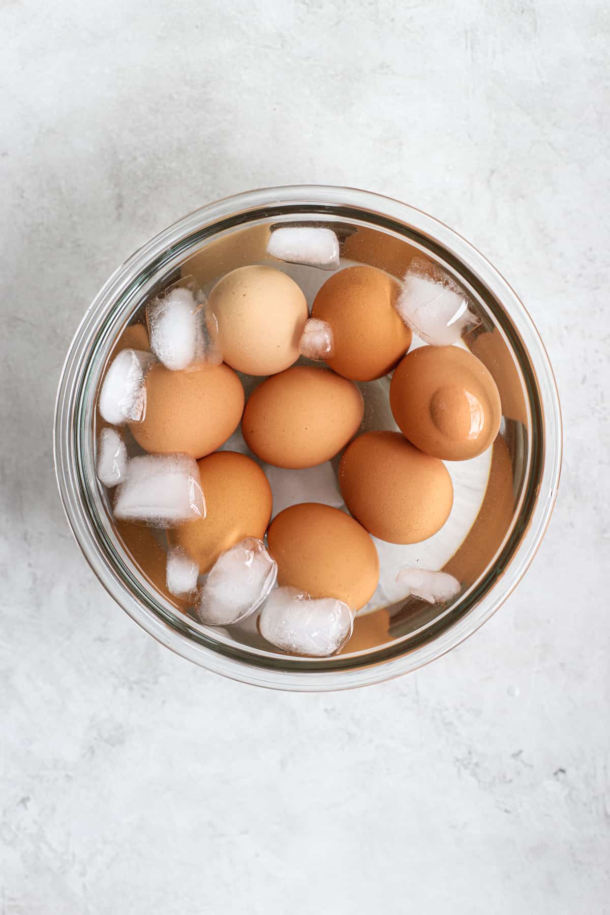 Ninja Foodi hard-boiled eggs in ice water in clear glass bowl