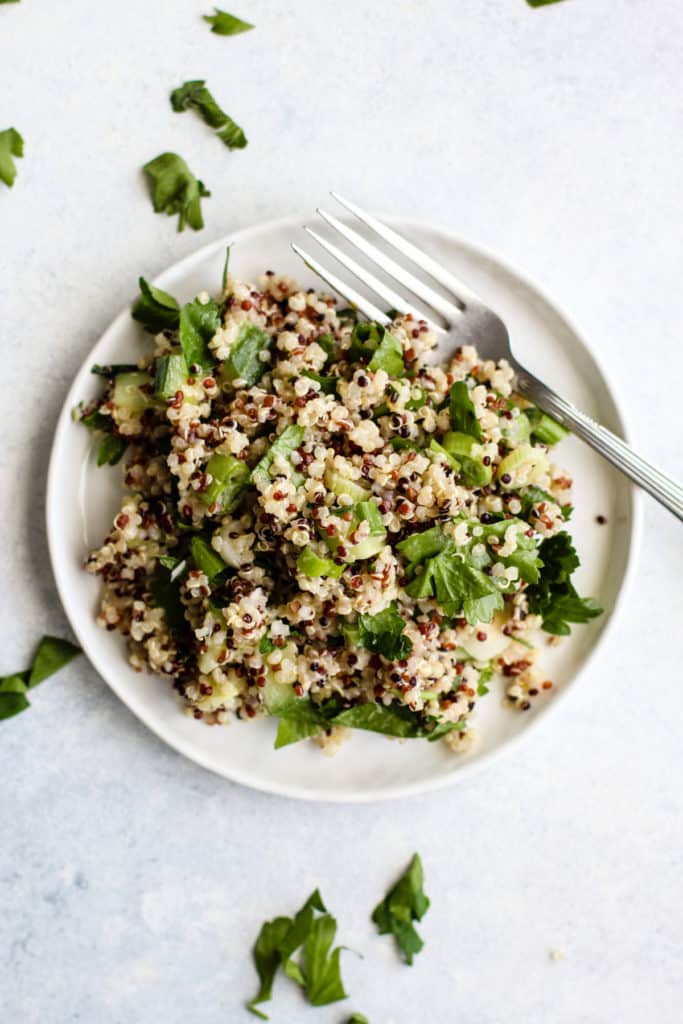 Simple detox quinoa salad on small white plate with fork