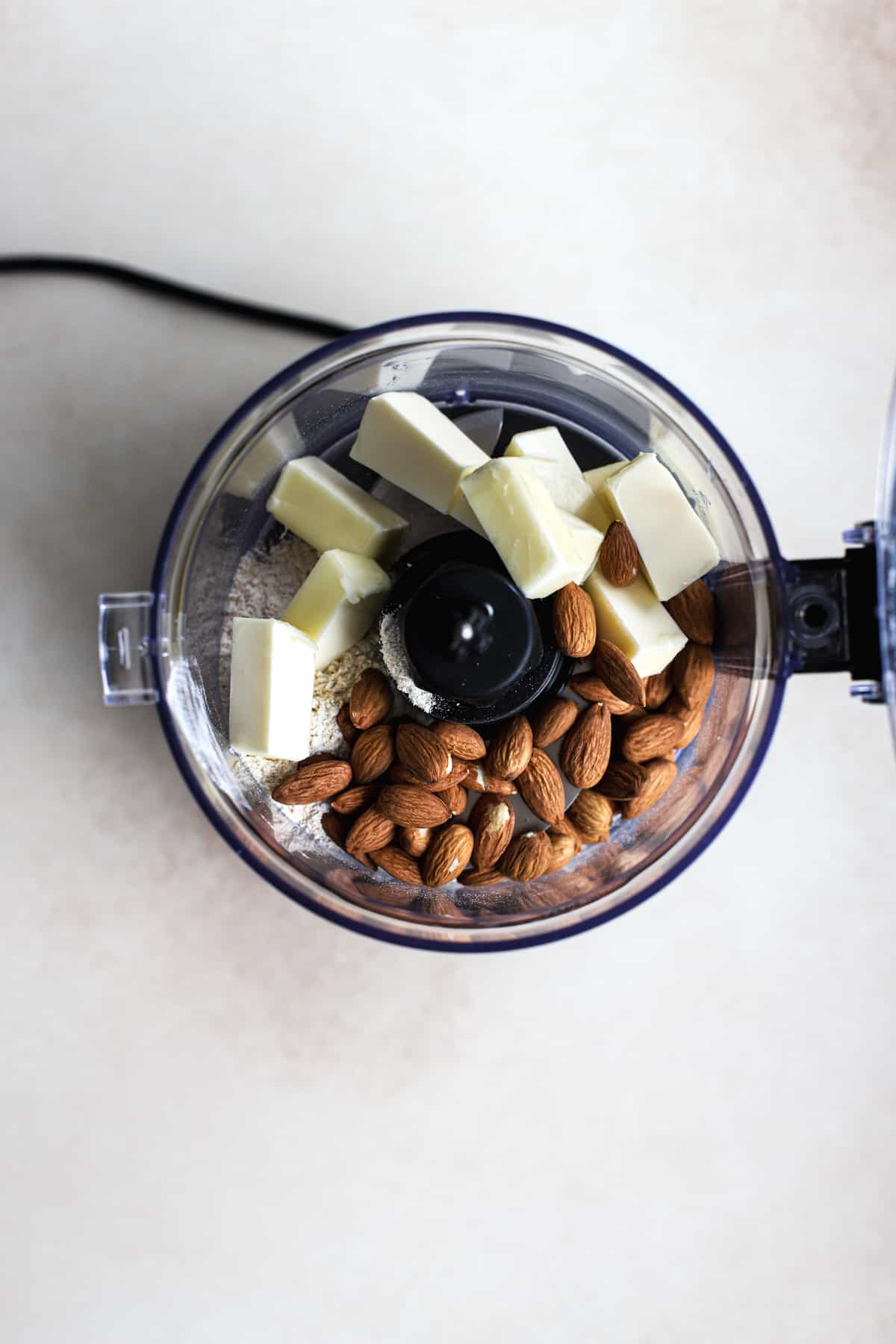 White whole wheat flour, almonds, and butter cubes in food processor