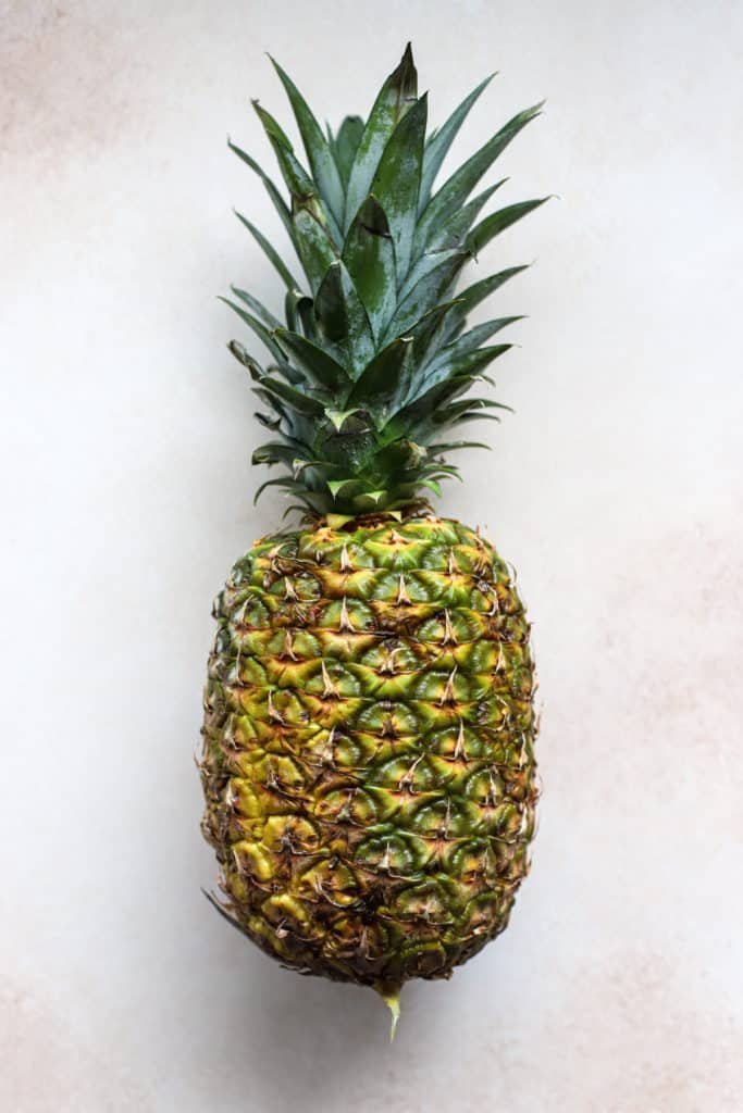 Whole fresh pineapple on beige and white surface