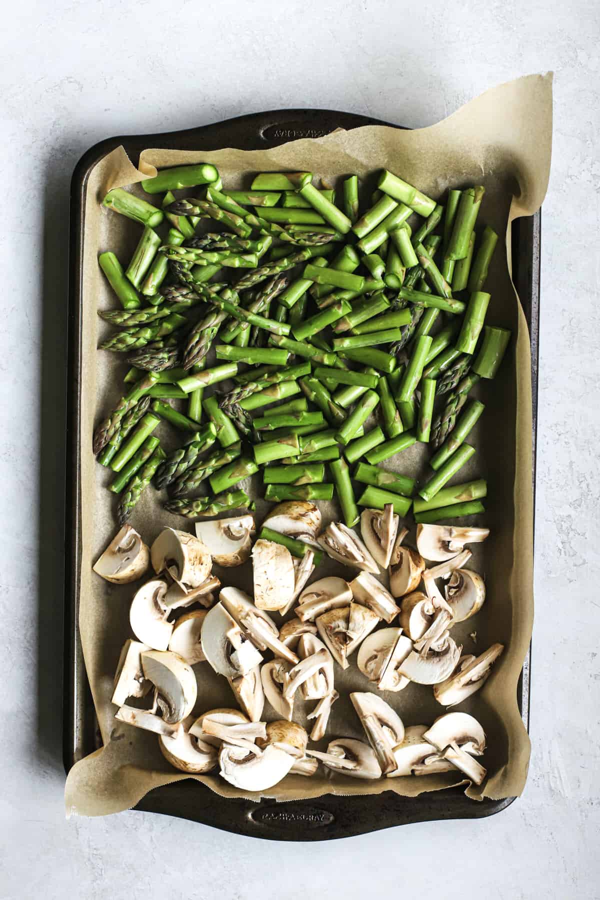 Chopped mushrooms and asparagus on parchment-lined sheet pan
