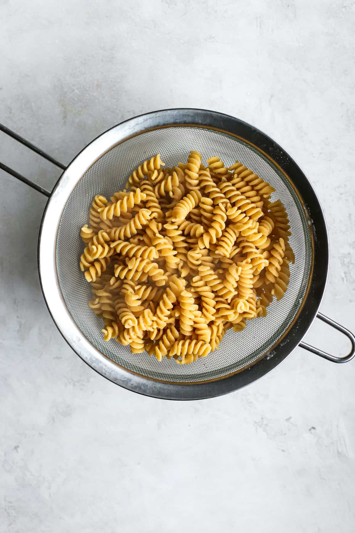 Cooked rotini in silver strainer