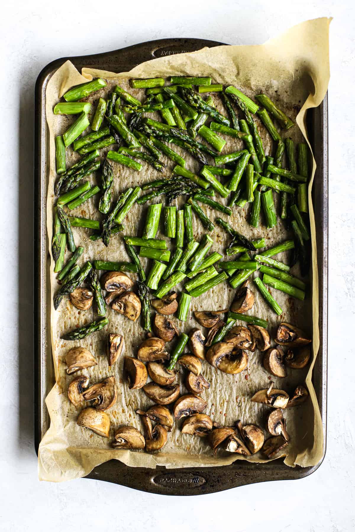 Roasted mushrooms and asparagus on parchment-lined sheet pan