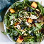 Peach blueberry salad in light blue bowl with teal linen on gray and white surface