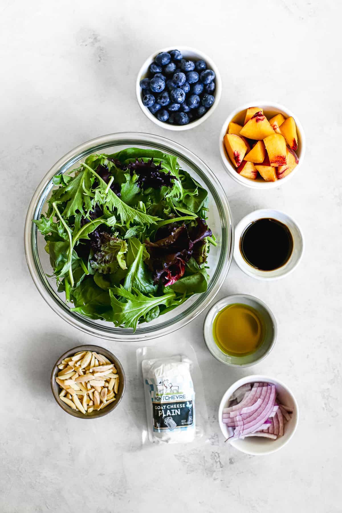 Mixed greens, blueberries, diced peaches, slivered almonds, goat cheese, red onions, aged balsamic, and olive oil measured into individual bowls